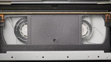 VHS video kaseti bir video kaydedicinin içine yerleştiriliyor ve oynatılıyor. Video kasetin klasik VHS mekanizması video başına bant takar. Retro video kaset bir video kasetinde döner. Eski bir film oynuyorum, yayın yapıyorum..