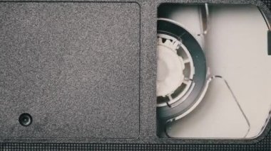 VHS video kasedi VCR kaydedicinin içine koyuldu ve oynatılıyor. Video kasetin klasik VHS mekanizması video başına bant takar. İçerideki eski video kaydedici. Eski video dosyası veya film çalma kavramı.