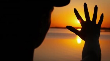 Genç bir kızın silueti gün batımına doğru uzanır, ağır çekimde. Kadın elinin arasına güneş ışınları yerleştiriyorum. Güneşte bir avuç, Tanrı 'ya inanmak. Hayal, mutluluk, özgürlük, zihinsel sağlık