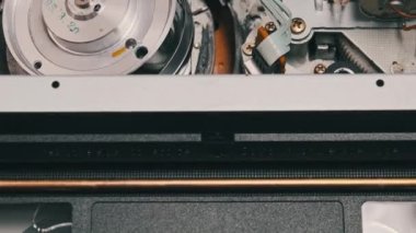 VHS video kasedi VCR kaydedicinin içine koyuldu ve oynatılıyor. Video kasetin klasik VHS mekanizması video başına bant takar. İçerideki eski video kaydedici. Eski video dosyası veya film çalma kavramı.