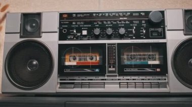 Masadaki klasik müzik kutusuyla ses kasedi çalıyorum. Masadaki iki kaset çalar üzerindeki erkek el ile oynatma düğmesine bas ve müzik dinle. Hoparlörlü gümüş retro radyo, 80 'ler.