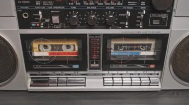 Masadaki klasik müzik kutusuyla ses kasedi çalıyorum. Masadaki iki kaset çalar üzerindeki erkek el ile oynatma düğmesine bas ve müzik dinle. Hoparlörlü gümüş retro radyo, 80 'ler.