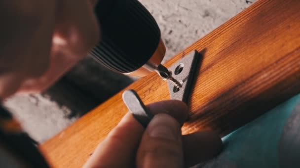 工匠用电动螺丝刀把一个自攻螺钉拧到木板上 用电钻把衣服挂在墙上的木板上 概念手工做的 你自己做 — 图库视频影像