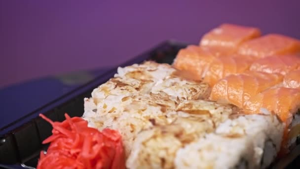プラスチックのデリバリーボックス内の寿司ロールは クローズアップを回転させます 新鮮な日本のロール わさびをプラスチック容器に回転させた寿司ボックス 食品の配達 持ち帰りの食品の概念 — ストック動画