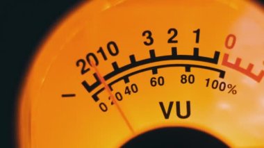 Sarı arka ışıklandırmalı ses sinyali seviyesinin analog yuvarlak ok göstergesi. Klasik retro VU ölçere yakın çekim. Eski ekipman, müzik ya da kayıt. Kayıt cihazındaki ses dB desibelleri
