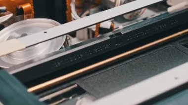 Kayıt cihazının içindeki video kaset oynatılıyor. Boş bir etiketle bir video kaseti yerleştirip oynatmaya başlıyorum. VHS mekanik video kasetçalar bant başlığı takıyor. VCR oynatıcı.