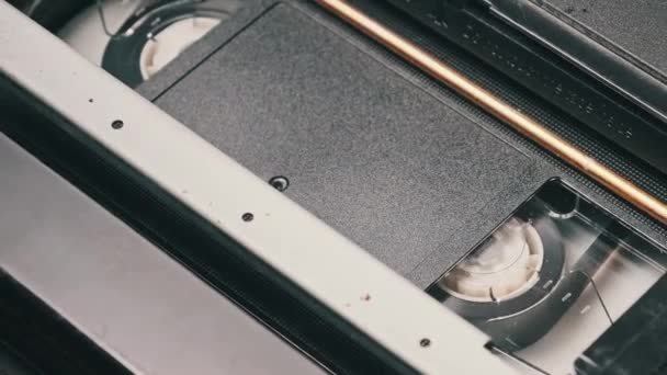 Vhsカセットは Vcrテープレコーダー トップビュー内で再生されます ビデオテープのリールが回転します 空白のタグを持つビデオカセットが再生を開始しています クローズアップ内の古いビデオレコーダー 古い映画を再生する — ストック動画