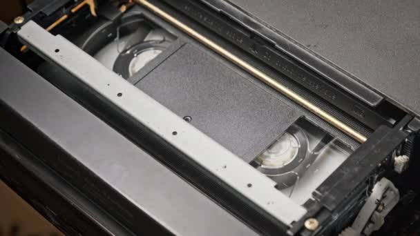 Vhsカセットは Vcrテープレコーダー トップビュー内で再生されます 動画リールが回転します 空の空白のタグを持つビデオカセットが再生を開始しています クローズアップ内の古いビデオレコーダー ヴィンテージ映画の再生 — ストック動画