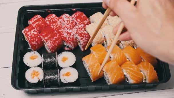 Sticks从寿司盒里取出寿司 在塑料盒里打滚 即食套餐的各种美味的日本寿司卷在运送容器 概念健康饮食 亚洲食物 外卖食物 — 图库视频影像