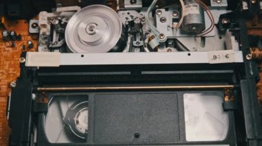 VHS video kaseti bir video kaydedicinin içine yerleştiriliyor ve oynatılıyor. Video kasetin klasik VHS mekanizması video başına bant takar. Retro video kaset bir video kasetinde döner. Eski bir film oynuyorum, yayın yapıyorum..