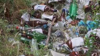 Orman çukurunda yasadışı plastik ve şişe çöplüğü. Doğada sentetik atık yığını. Ormanda bir sürü çöp var. İnsanlar tarafından yere atılan ıvır zıvırlar. Ekolojik felaket