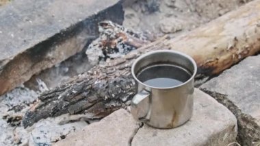 Kamp ateşinde kendi kendine aromatik kahve yapan kupa, yakın plan. Kaynatılmış demir bardak kahvenin arka planı. Ormanda şenlik ateşinde kahve yapmak. Yürüyüş, dışarıda piknik.
