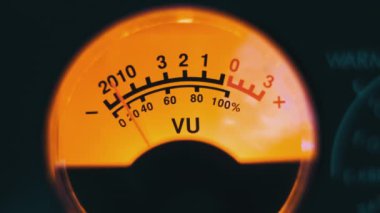 Sarı arka ışıklandırmalı ses sinyali seviyesinin klasik analog ok göstergesi. Analog VU ölçere yakın çekim. Retro ekipman, müzik çalma ya da kayıt. Ses düzeyi ile ses düzeyi senkronize ediliyor