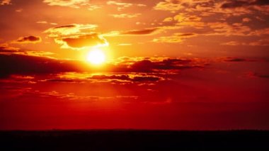 Turuncu gökyüzünde bulutlarla birlikte harika bir gün batımı, Timelapse. Parlak turuncu güneş ufuk çizgisinde katmanlı bulutların arkasında hareket ediyor. Destansı bulut uzayı, canlı bir renk. Zaman aşımı. Güzel gün batımı