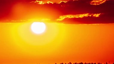 Turuncu gökyüzünde bulutlarla birlikte harika bir gün batımı, Timelapse. Parlak turuncu güneş ufuk çizgisinde katmanlı bulutların arkasında hareket ediyor. Destansı bulut uzayı, canlı bir renk. Zaman aşımı. Güzel gün batımı