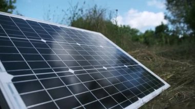 Taşınabilir güneş paneli doğada, yakın planda, yerde yatıyor. Turizm ve kamp alanları için güneş enerjisi. Çimenlerdeki bir güneş paneli güneşli bir yaz gününde enerji üretir. 4K
