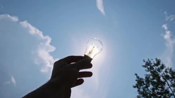 Pov Silhouette Male Hand Holds Light Bulb Bright Sun Blue — Stock Video