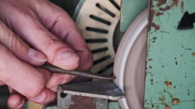 Elektrikli çarkın metal gıcırtısı. Parlak kıvılcımlar metal bir parçayı makinelemekten geliyor. Bir atölyede eski aşındırıcı tekerlek üzerinde çalışan bir zanaatkar. Çelik işleme, yakın çekim, yavaş çekim.