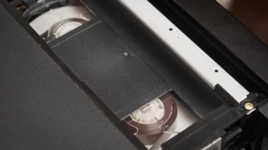 Kayıt cihazının içindeki video kaset oynatılıyor. Boş bir etiketle bir video kaseti yerleştirip oynatmaya başlıyorum. VHS mekanik video kasetçalar bant başlığı takıyor. VCR oynatıcı.