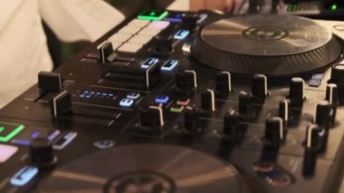DJ gece partisinde DJ kumandayı kullanarak müzik çalar. Mikser konsolunda dans müziği karıştırıyorum. DJ elleri modern dijital düğmeleri, faders, jog tekerlekleri ve çok renkli aydınlatma düğmelerini kuruyor