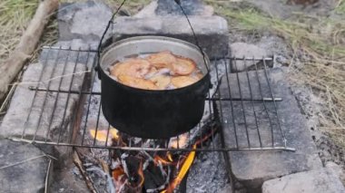 Mantarlar kamp ateşinde tencerede pişirilir. Birçok chanterelles mantarı, doğada kendi kendini yetiştirmiş bir ocağın üzerinde açık ateşte kaynatılır. Ormanda kamp yaparken yemek pişirmek. 4K
