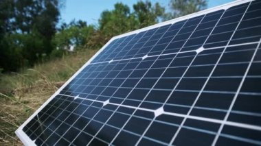 Taşınabilir güneş paneli doğada, yakın planda, yerde yatıyor. Turizm ve kamp alanları için güneş enerjisi. Çimenlerdeki bir güneş paneli güneşli bir yaz gününde enerji üretir. 4K