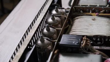 Ev yapımı ses yükselticinin içinde parlayan radyo tüpleri. Eski devreler, radyo parçaları, kablolar. Amplifikatör panosundaki elektronik vakum tüpleri. Eski moda valf yükselticisi. Eski moda lamba. 4K