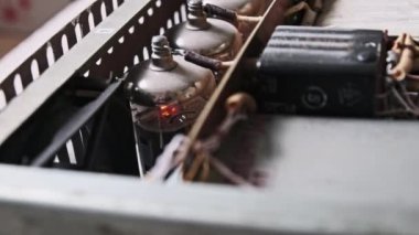 Bağbozumu ses yükselticisinin içinde ısınan ses amfi tüpleri. Müzik amplifikatöründe parlayan radyo vanaları. Radyo parçaları ve yüksek voltaj kablolarıyla ev yapımı ses yükselticinin eski moda devresi..