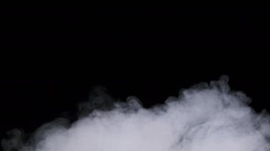 Duman ya da buhar bulutları yavaş çekimde siyah bir arkaplanda yükselir. Havada süzülen beyaz buhar sisi. Gerçek atmosferik etki, soyut duman dokusu parçacıkları. Uzayı kopyala 4K