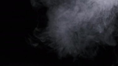 Ağır çekimde siyah arka planda duman veya buhar akımı. Patlama buharı. Beyaz duman bulutları yükseliyor. Yüzen sis. Gerçek atmosferik etki, soyut duman dokusu parçacıkları. Boşluğu kopyala
