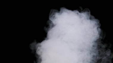 Ağır çekimde siyah arka planda sigara içmek. Patlama buharı. Gerçek bir beyaz duman bulutu ya da buhar yükselir. Yüzen sis. Atmosferik etki, soyut duman dokusu parçacıkları, FX. Boşluğu kopyala.