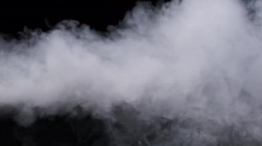 Ağır çekimde siyah arka planda duman veya buhar akımı. Patlama buharı. Beyaz duman bulutları yükseliyor. Yüzen sis. Gerçek atmosferik etki, soyut duman dokusu parçacıkları. Boşluğu kopyala