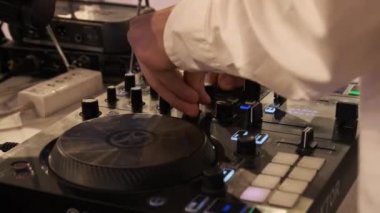 DJ gece partisinde DJ kumandayı kullanarak müzik çalar. Mikser konsolunda dans müziği karıştırıyorum. DJ elleri modern dijital düğmeleri, faders, jog tekerlekleri ve çok renkli aydınlatma düğmelerini kuruyor