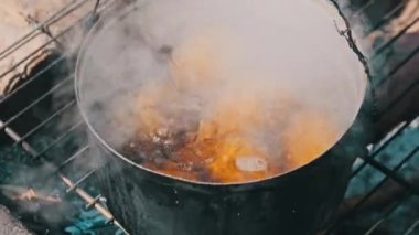 Bir sürü genç patates, kendi yaptığı bir ocakta açık ateşte kaynar suda kaynatılır. Patatesler doğada bir kamp ateşinde tencerede suda pişirilir. Ormanda kamp yaparken yemek pişirmek..