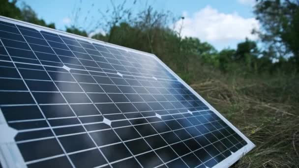 ポータブルソーラーパネルは 屋外の自然の中で地面に接近しています 観光やキャンプ場のためのソーラーエネルギー 草の上の1つの太陽電池パネルは 夏の晴れた日に発電する 4Kについて — ストック動画