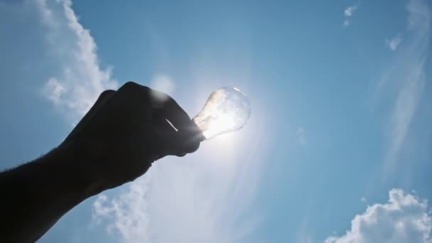 Male Hand Holds Throws Incandescent Light Bulb Sky Bright Sun — Stock Video