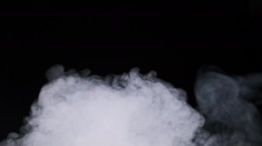 Ağır çekimde siyah arka planda duman veya buhar akımı. Patlama buharı. Beyaz duman bulutları yükseliyor. Yüzen sis. Gerçek atmosferik etki, soyut duman dokusu parçacıkları. Boşluğu kopyala