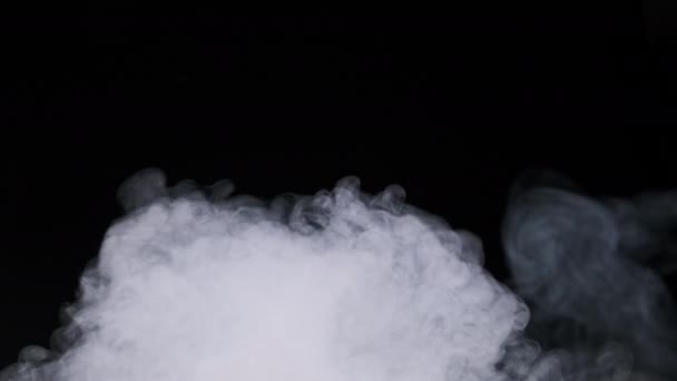 jet de fumée ou de vapeur sur fond noir au ralenti 4K. De la vapeur d'explosion. Des nuages de fumée blanche se lèvent. Brouillard flottant. Effet atmosphérique réel, particules abstraites de texture fumée. Espace de copie