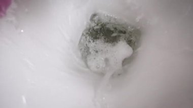 Yavaş çekimde sifonu çekmek, yakın plan. Modern banyodaki tuvalette dönen su manzarası. Kamera dönüyor ve uzaklaşıyordu. Su kanalizasyon borusuna akıyor, su tasarrufu..