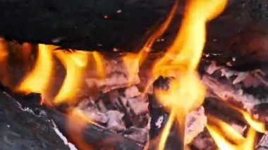 Kamp ateşi akşamları doğada yavaş çekimde yanar. Açık havada yanan ağaç kütükleri ve kıvılcımları olan sarı şenlik ateşi. Çam ağacı ateşi ve parlayan kömür. Bir orman yangınının arka planı.