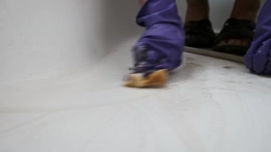 Kirli tuvaleti turuncu süngerle yavaş çekimde temizleyen bir kadın. Mavi lastik eldivenli kadın elleri banyoyu siliyor. Küvet yüzeyini deterjanlarla temizliyorum. Ev işi, temizlik konsepti