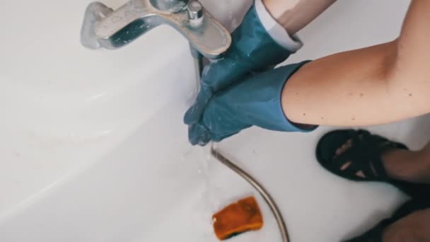 女性はトイレを掃除した後 水の下でゴム手袋で手を洗います ゆっくりとした動きでトイレ掃除のコンセプト スムーズなカメラモーション クローズアップ ハウスワーククリーニング — ストック動画