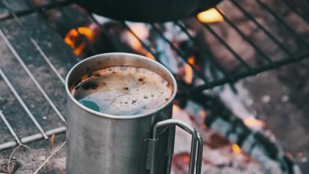 自然の中でキャンプファイヤーでアロマティックなコーヒーを自作するムグ キャンプファイヤーによって準備された香りの醸造されたコーヒーが付いている観光客の鉄のマグの背景 ハイキング 森の屋外ピクニック — ストック動画