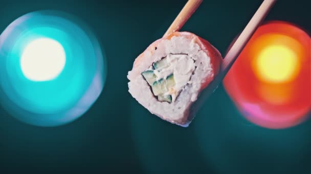 拿着一个寿司卷 用木棍做寿司 展示色彩斑斓的背景 用筷子的人的手展示了新鲜的日本寿司和鲑鱼及费城奶酪 海鲜食品 — 图库视频影像