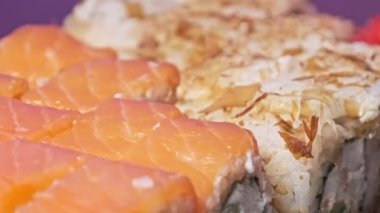 Suşi plastik bir kutuda yuvarlanır ve yakın plan çekilir. İçinde taze Japon dürümleri, zencefil ve vasabi olan suşi kutusu teslimat plastik bir kapta dönüyor. Asya yemekleri, paket yemek, sağlıklı yemek.