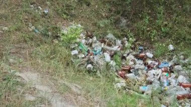 Ormanda plastik ve şişe çöplüğü var. Doğadaki sentetik atık yığını, ormanlardaki insan kirliliği. Yasa dışı çöpler yere dökülüyor. Orman bölgesinde bir sürü çöp atılıyor..