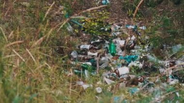 Orman çukurunda yasadışı plastik ve şişe çöplüğü. Ormanların insan kirliliği. Doğada sentetik atık yığını. Tahtada bir sürü çöp var. İnsanlar tarafından bir yere atılan çöpler.