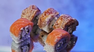 Suşi için çubuk kullanarak sete bir suşi rulosu koy, yakın plan. Yemeye hazır taze Japon unagi suşisi ve somon ve Philadelphia peynirli rulo. Geleneksel deniz ürünleri mutfağı