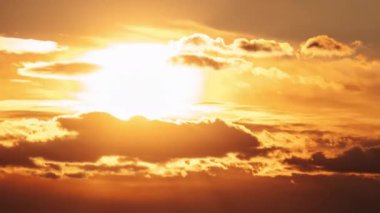 Gün batımı turuncu gökyüzünde bulutlarla hareket ediyor, zaman ayarlı. Muhteşem parlak turuncu güneş ufuk çizgisinde katmanlı bulutların arkasında hareket ediyor. Destansı bulut uzayı, canlı bir renk. Zaman aşımı. Gün batımı 4K