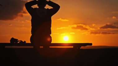 Genç bir kadının silueti ellerini günbatımına doğru kaldırıyor, ağır çekimde. Doğada hayatın tadını çıkaran ve güneşin batmasını bekleyen genç bir kız. Özgürlüğü, mutluluğu, akıl sağlığını kavrayın.